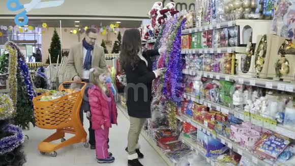 在购物中心为圣诞树买装饰品的年轻家庭视频的预览图