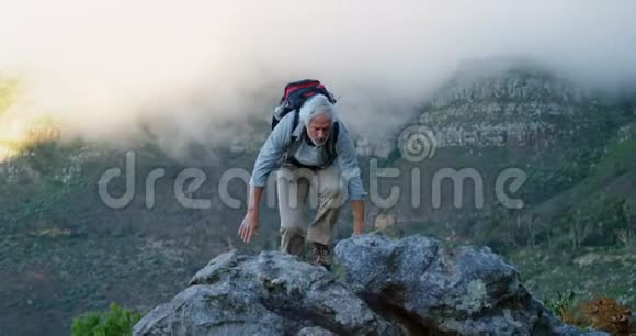 4k乡下的岩石上举着双臂的老人视频的预览图
