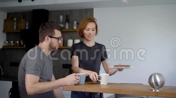 可爱的年轻夫妇在厨房喝咖啡丈夫和妻子并排坐在一个现代的室内视频的预览图