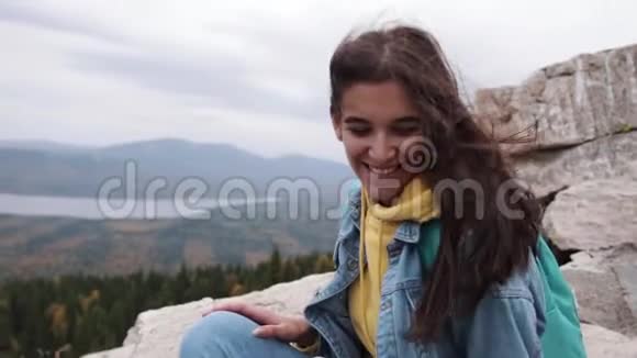 快乐的旅行者时髦女孩有着风的头发微笑着站在桑尼山顶时尚女性发型视频的预览图