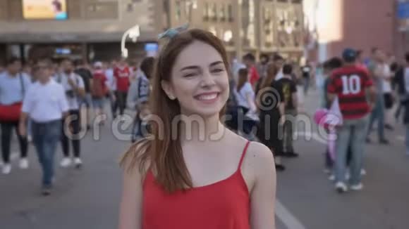 节日期间站在街上的年轻美女的肖像抚摸着头发微笑着人群走来走去视频的预览图