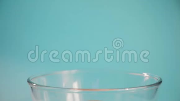 爆米花被装进蓝色背景上的玻璃透明碗里视频的预览图