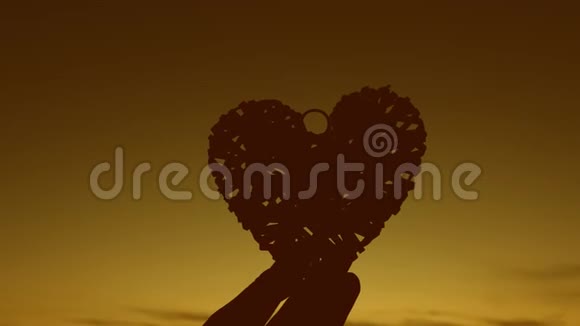 女孩在日落时双手捧着心浪漫又有爱心的女人视频的预览图