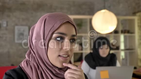 年轻穆斯林妇女戴着头巾在现代办公室工作思考两名妇女坐在笔记本电脑上打字的肖像视频的预览图