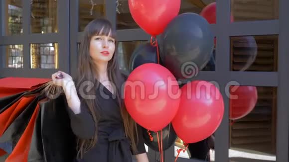 购物后红唇的购物狂女孩在街上拿着气球和很多包裹视频的预览图