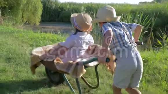 孩子们在户外玩独轮车小男孩在村庄的湖边骑着小女孩视频的预览图
