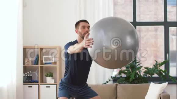 男人在家里用球锻炼和蹲视频的预览图