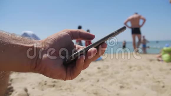 在海滩上接近使用移动智能手机的人黑屏电话短信视频电话海滨假日视频的预览图