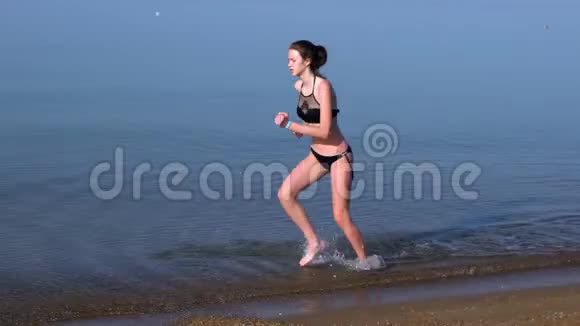 苗条的年轻女子在浅海中奔跑视频的预览图