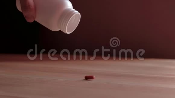 红色胶囊从桌子上的罐子里倒出来视频的预览图