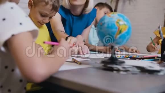 小学或幼儿园的孩子在教室里画画老师帮忙年轻白种人的肖像视频的预览图