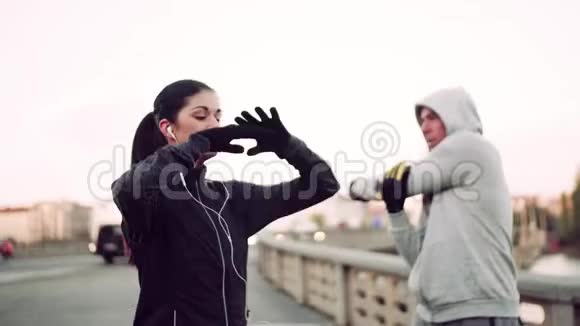 一对合适的跑步者在布拉格市的桥上做户外伸展运动视频的预览图