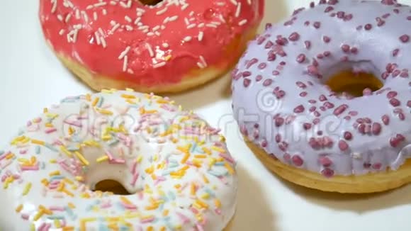 将美味的红白紫甜甜圈的视频贴在白色盘子上上面撒着五颜六色的花视频的预览图