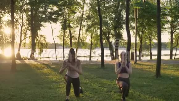 两个年轻漂亮的女人蹲在公园里减肥健身模特锻炼美丽的景色背景视频的预览图