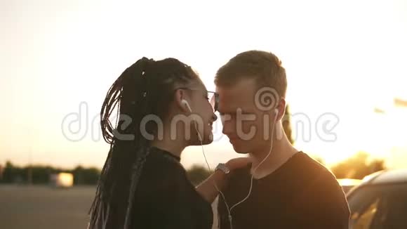 年轻有魅力的夫妇一起听白色耳机的音乐站在外面的大街上跳舞接吻视频的预览图