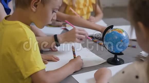 一组小朋友和一位老师用彩色铅笔在白纸上画画小学儿童在视频的预览图