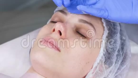 美容师用泡沫清洁剂涂在年轻妇女的客户的脸上脸和双手特写视频的预览图
