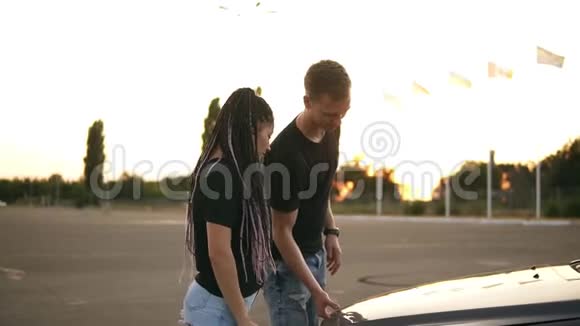一对年轻夫妇在停车区的公路旅行中停了下来男孩打开车盖指着视频的预览图