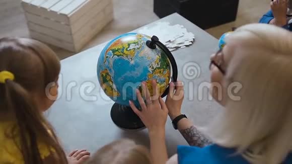 上景一位有纹身的时尚老师给孩子们看一个地球仪老师在地球上和孩子们讨论地理问题视频的预览图