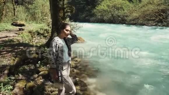 夏天黑发姑娘在河边的高树下休息视频的预览图