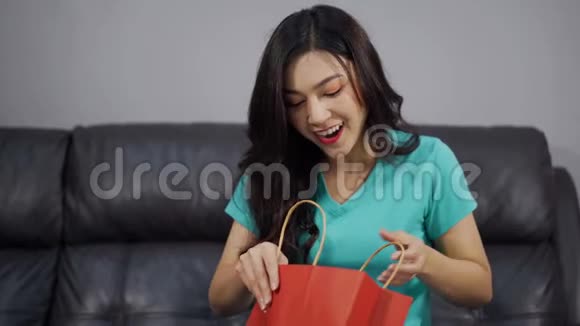 客厅里的购物袋里的惊喜女人打开礼物视频的预览图