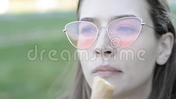 公园吃草莓冰淇淋的快乐年轻女人视频的预览图