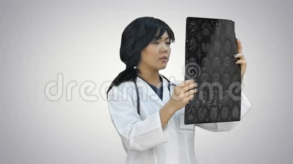 身穿白大褂听诊器的亚洲女医生在白色背景下看x光片视频的预览图