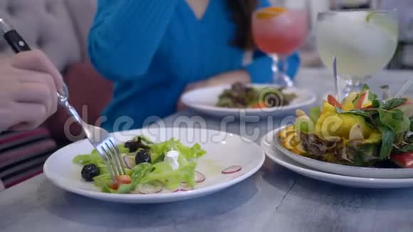 健康的生活方式节食的女孩在咖啡馆的餐桌上吃白色盘子里的希腊沙拉视频的预览图