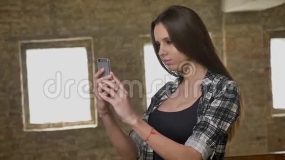 年轻漂亮美女留长发用手机自拍选角度拍照砖房视频的预览图
