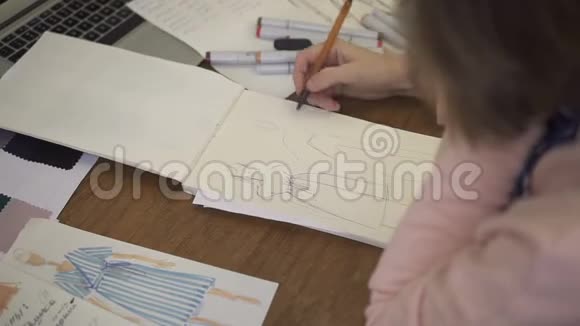 在纸笔上女时装设计师制作服装草图视频的预览图