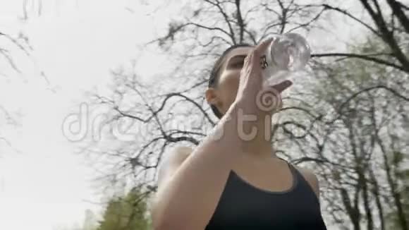 年轻健康的女孩夏天在公园里喝水健康的生活方式运动理念底景相机圆步视频的预览图