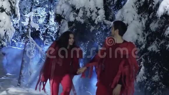 穿着红衣服的可爱青年男女在白雪皑皑的冬木中慢慢行走视频的预览图