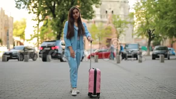 一个女人带着手提箱在城里等出租车视频的预览图