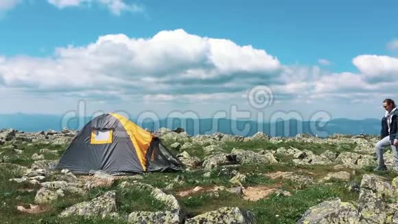 一对年轻夫妇在阳光明媚的夏日在大自然的营地里休息帐篷在山上一片绿色的草地上游客来了视频的预览图