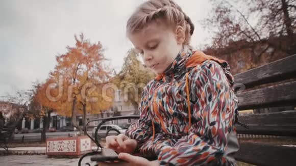秋天路附近有智能手机的小女孩视频的预览图