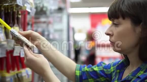 一个年轻的女人在超市里挑选并买了一把画笔视频的预览图