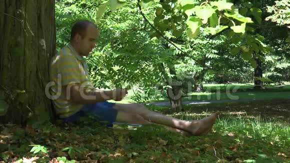 夏天人们在绿树下的绿色公园里看书4K视频的预览图