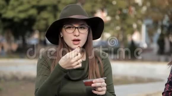 一个年轻的女孩坐在公园里正在尝试一种美味的酱汁散步吃饭视频的预览图