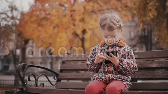 秋天路附近有智能手机的小女孩视频的预览图