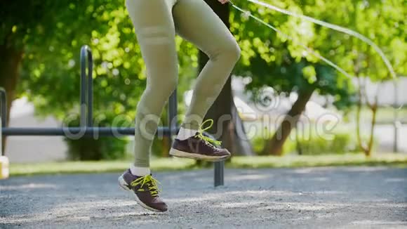 夏天公园里穿着紧身裤和紫色运动鞋的运动女子跳绳视频的预览图