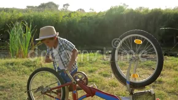 好奇的孩子在农村用背景自然的背光旋转自行车和脚踏车视频的预览图