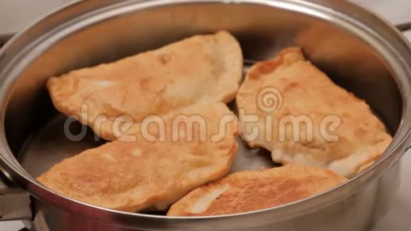 漂亮的油炸肉馅饼是用热菜油在锅里煮熟的特写镜头有金属光泽的盘子视频的预览图