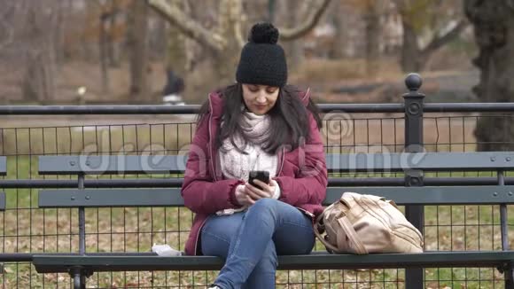 年轻女子坐在纽约中央公园的长椅上视频的预览图
