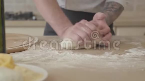 现代厨房里年轻的比萨饼师穿着厨师制服熟练地捏着面团做比萨饼橄榄油视频的预览图