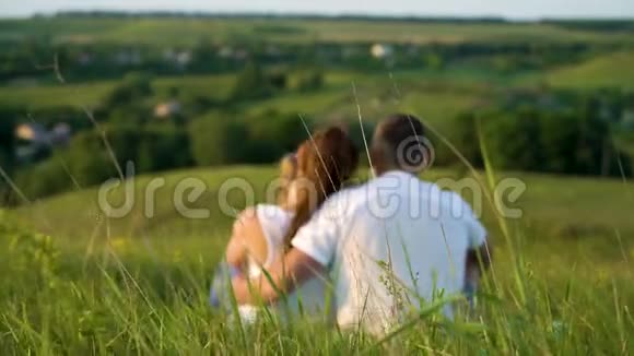 一对怀孕的夫妇和一个蹒跚学步的女儿一起在户外休闲后景视频的预览图