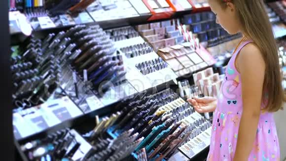 化妆品店漂亮的女孩孩子仔细考虑化妆品在美容店时尚小女孩视频的预览图