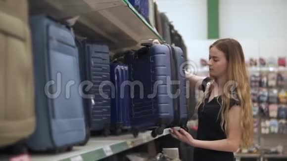 苗条的女孩正从一个超市的货架上拿着一个大箱子来检查视频的预览图