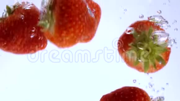 美丽的慢动作红草莓掉进水里视频的预览图