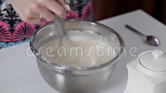 一个女人把杯子里的牛奶倒入有面团的碗里女孩准备煎饼饼干面团视频的预览图