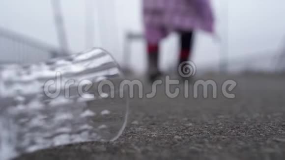 铺在人行道上的玻璃特写一位衣衫褴褛的老妇人在模糊的地面上行走视频的预览图